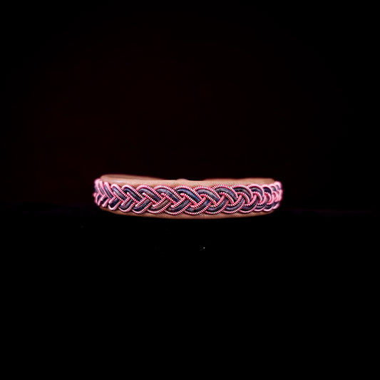 Bracelet with pink and black braided design on a black background